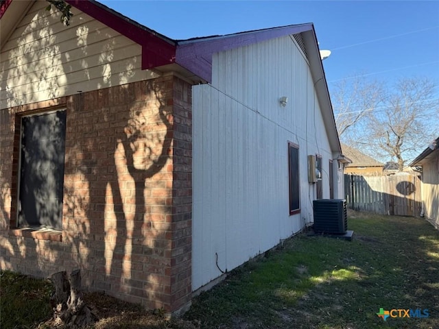 view of side of home with central air condition unit and a lawn