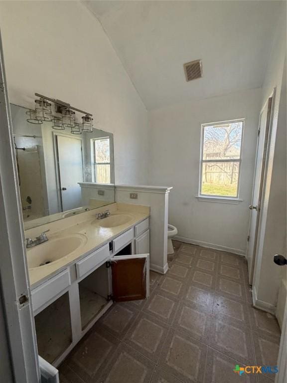 bathroom featuring vanity, vaulted ceiling, plenty of natural light, and toilet