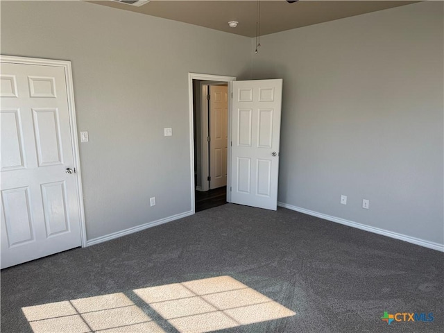 unfurnished bedroom featuring baseboards and dark colored carpet