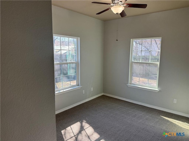 empty room with baseboards, dark colored carpet, and ceiling fan