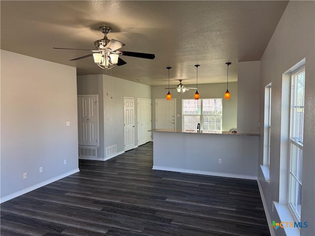 kitchen with hanging light fixtures, dark wood-style floors, visible vents, and baseboards