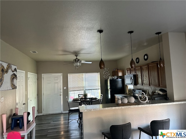 kitchen featuring black appliances, kitchen peninsula, hanging light fixtures, and dark hardwood / wood-style floors