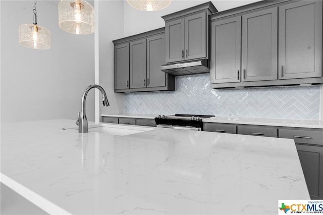 kitchen with stainless steel range, sink, tasteful backsplash, decorative light fixtures, and gray cabinets