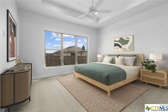 bedroom with a tray ceiling, ceiling fan, and carpet flooring