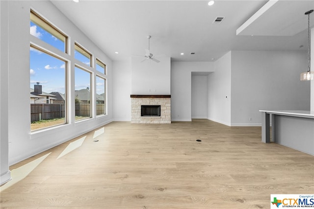 unfurnished living room featuring ceiling fan, light wood-type flooring, and a fireplace