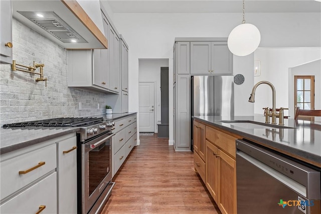 kitchen with a sink, light wood-style floors, stainless steel appliances, custom range hood, and backsplash