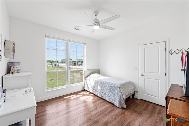 bedroom featuring baseboards, wood finished floors, visible vents, and ceiling fan