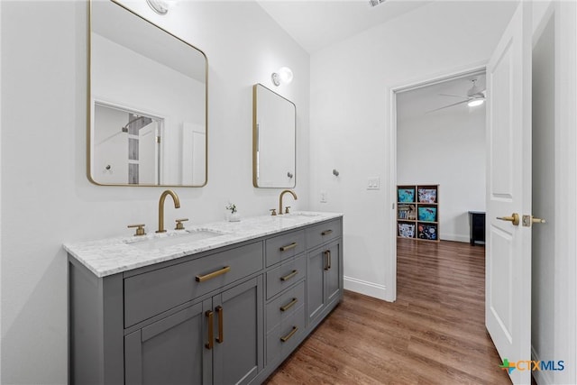 full bathroom featuring baseboards, wood finished floors, a sink, and double vanity