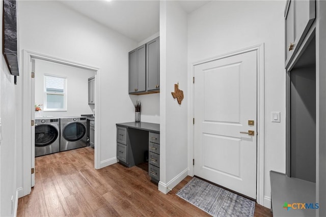 clothes washing area featuring separate washer and dryer, cabinet space, and wood finished floors
