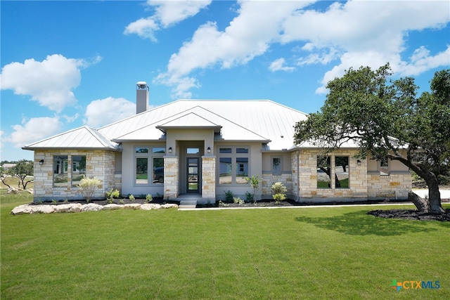 view of front of house with a standing seam roof, metal roof, stucco siding, a chimney, and a front yard