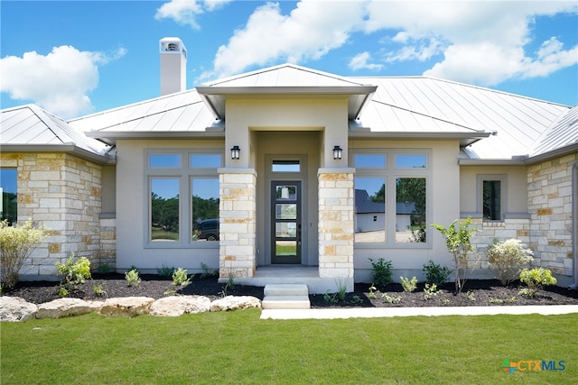 view of front facade with stone siding, a standing seam roof, metal roof, and stucco siding