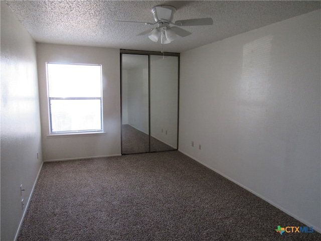 unfurnished bedroom with a textured ceiling, carpet, ceiling fan, and a closet