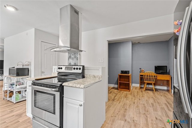 kitchen with white cabinetry, appliances with stainless steel finishes, light hardwood / wood-style floors, and wall chimney range hood