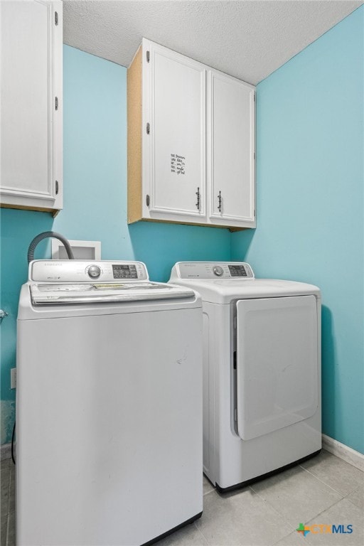 laundry area with washing machine and dryer, cabinets, and a textured ceiling