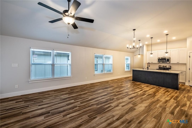 unfurnished living room featuring lofted ceiling, sink, ceiling fan with notable chandelier, and dark hardwood / wood-style flooring