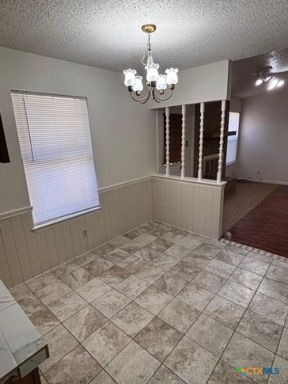 3206 Tallwood Dr, Killeen, TX 76549 - unfurnished dining area featuring a chandelier, a wainscoted wall, and a textured ceiling