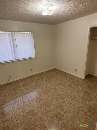 3206 Tallwood Dr, Killeen, TX 76549 - unfurnished bedroom featuring a textured ceiling, a closet, and tile patterned floors