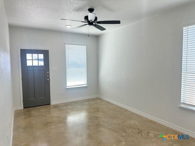 foyer entrance featuring a textured ceiling, plenty of natural light, baseboards, and finished concrete floors