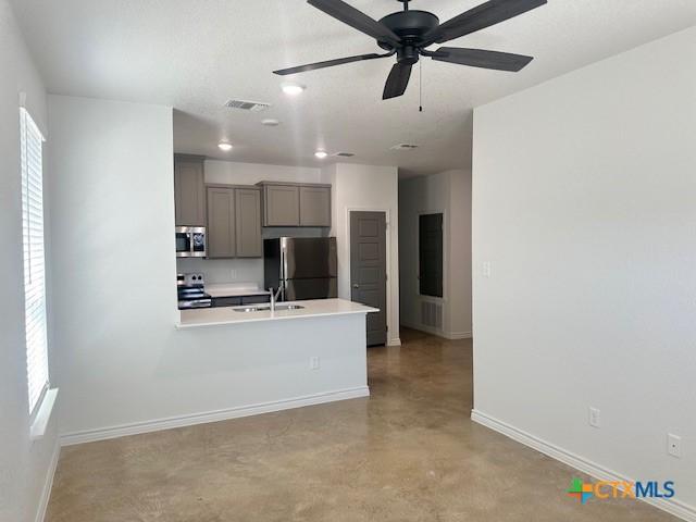 kitchen with light countertops, visible vents, appliances with stainless steel finishes, finished concrete floors, and a sink