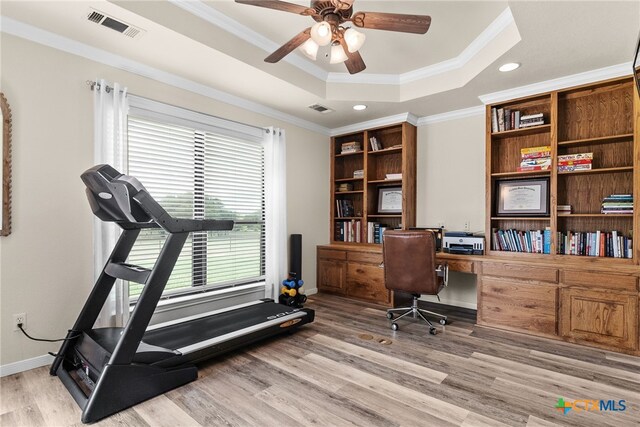 home office featuring built in desk, a raised ceiling, light hardwood / wood-style floors, and ornamental molding