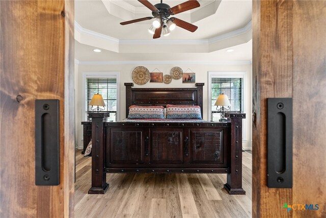 bar featuring ornamental molding, light hardwood / wood-style floors, plenty of natural light, and a tray ceiling