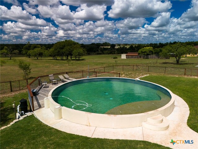 view of pool with a rural view and a lawn