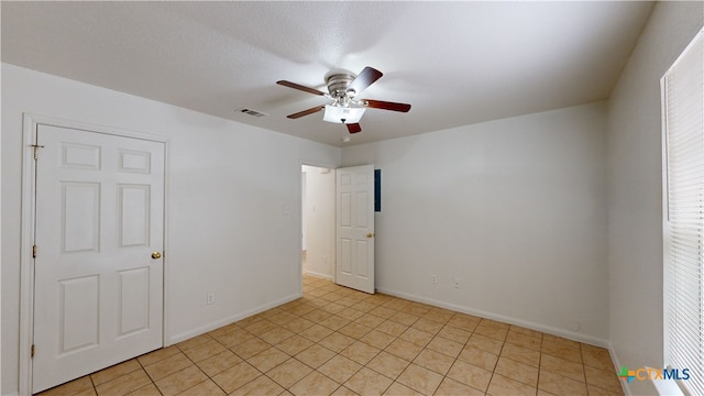 unfurnished room with baseboards, visible vents, and a ceiling fan