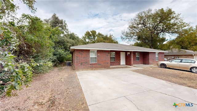 ranch-style house featuring cooling unit and brick siding