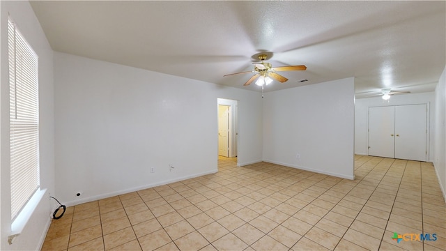 unfurnished room featuring visible vents, light tile patterned flooring, a ceiling fan, and baseboards