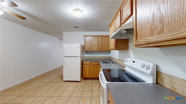 kitchen featuring white appliances, visible vents, a textured ceiling, under cabinet range hood, and a sink