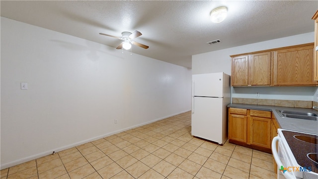 kitchen with ceiling fan, a textured ceiling, white appliances, a sink, and visible vents