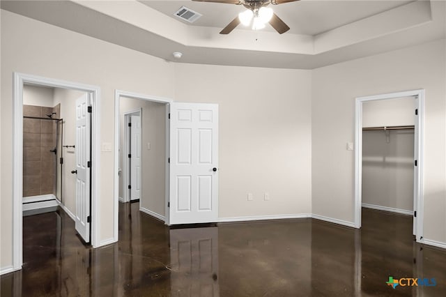 unfurnished bedroom featuring connected bathroom, a tray ceiling, ceiling fan, and a spacious closet