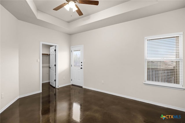 unfurnished room with ceiling fan and a tray ceiling