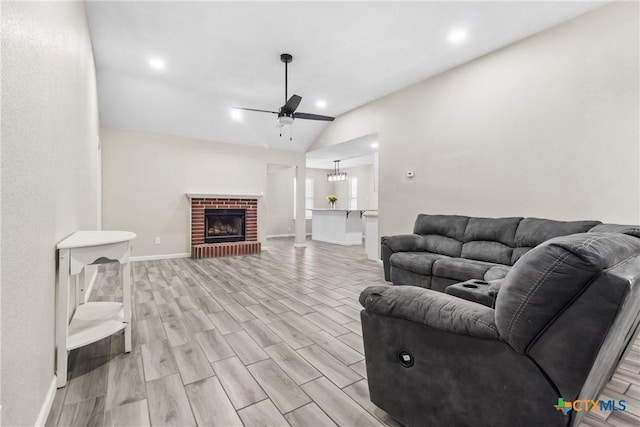 living room with a brick fireplace, vaulted ceiling, light hardwood / wood-style floors, and ceiling fan