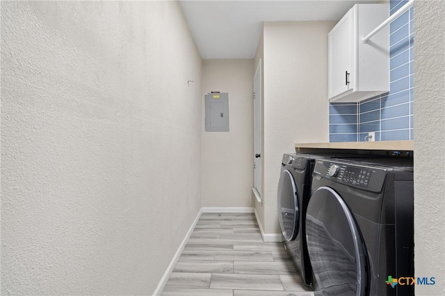 laundry area featuring light hardwood / wood-style flooring, washer and clothes dryer, electric panel, and cabinets