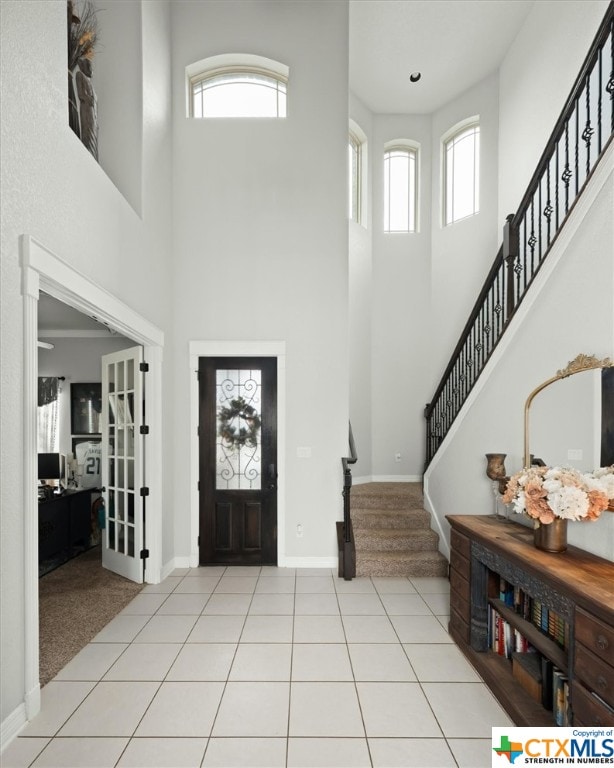 entrance foyer featuring a wealth of natural light, a towering ceiling, and light tile patterned flooring