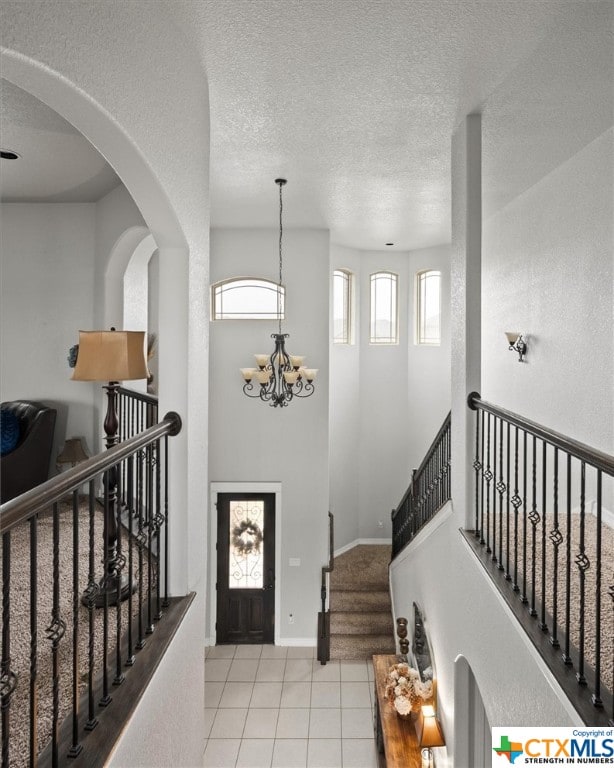 tiled entryway featuring a textured ceiling and a notable chandelier