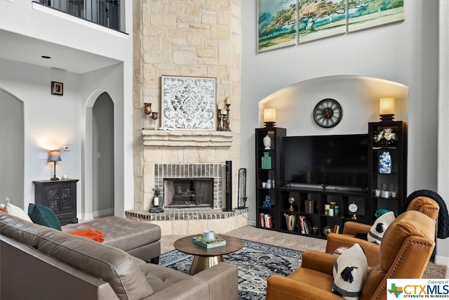 living room with a towering ceiling and a large fireplace