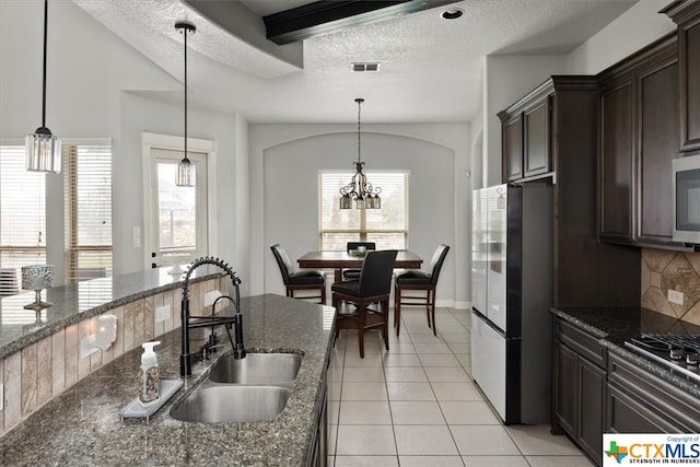 kitchen featuring dark stone countertops, appliances with stainless steel finishes, sink, and a textured ceiling