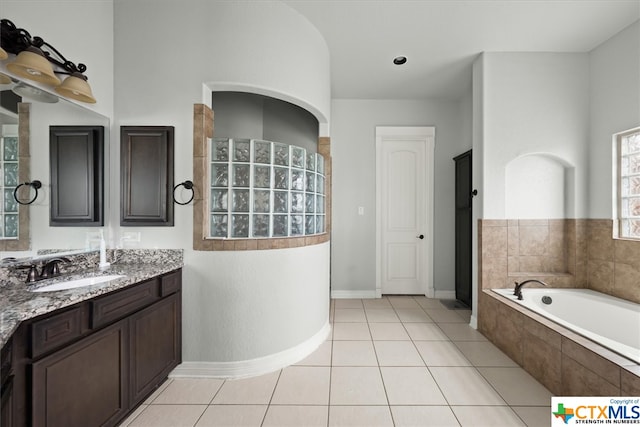 bathroom featuring vanity, tile patterned flooring, and tiled tub