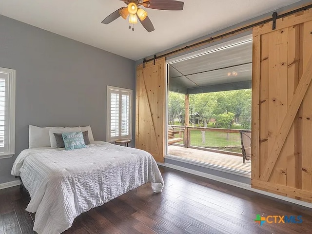 bedroom with a barn door, baseboards, ceiling fan, dark wood-type flooring, and access to outside