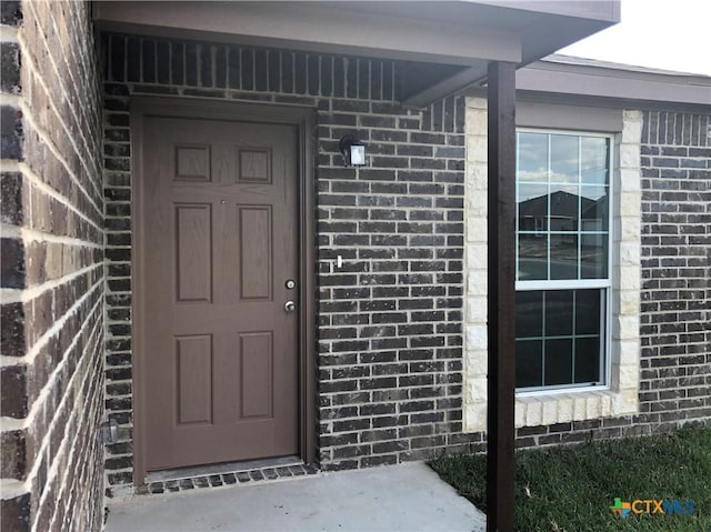 entrance to property featuring brick siding