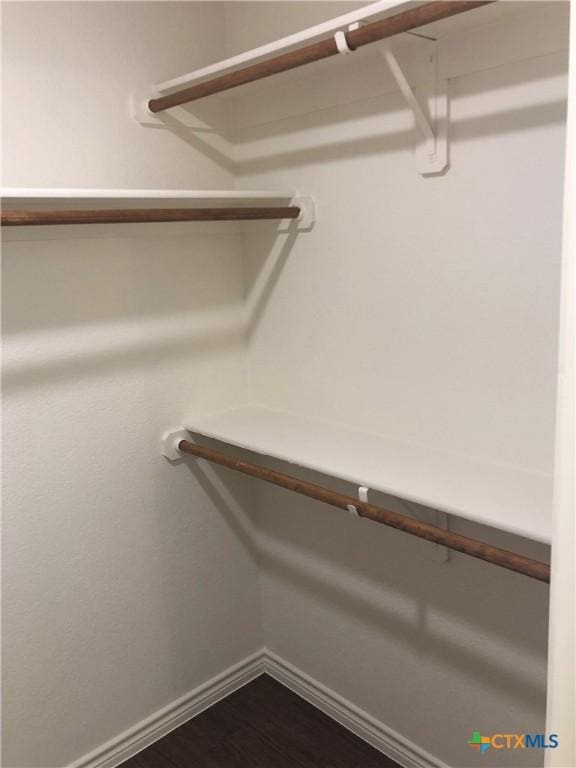 walk in closet with dark wood-type flooring