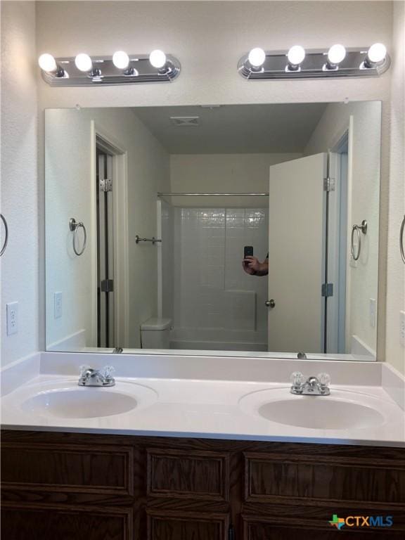 full bathroom featuring walk in shower, double vanity, and a sink