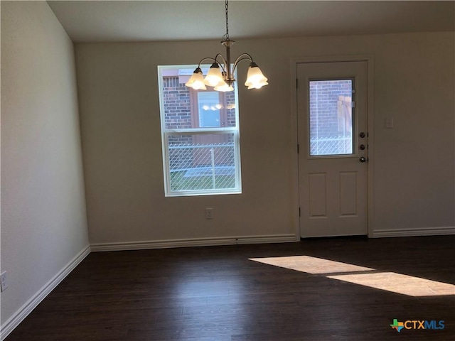 unfurnished dining area with wood finished floors, a chandelier, and baseboards