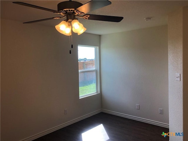 empty room with baseboards, ceiling fan, and dark wood-style flooring