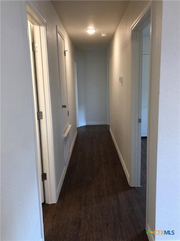 corridor featuring wood finished floors and baseboards