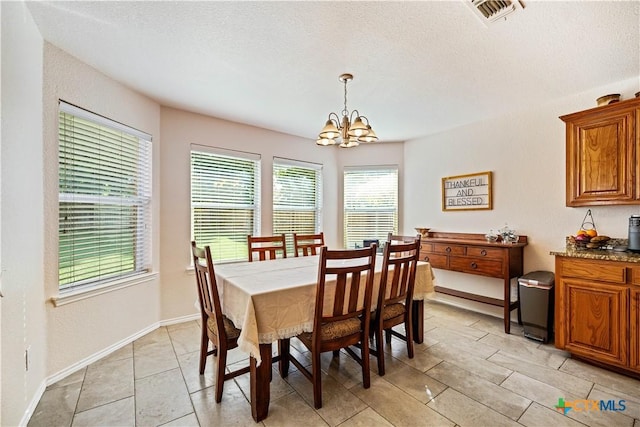 dining room with a textured ceiling, baseboards, visible vents, and a notable chandelier