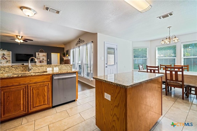 kitchen featuring dishwasher, brown cabinetry, a sink, and visible vents