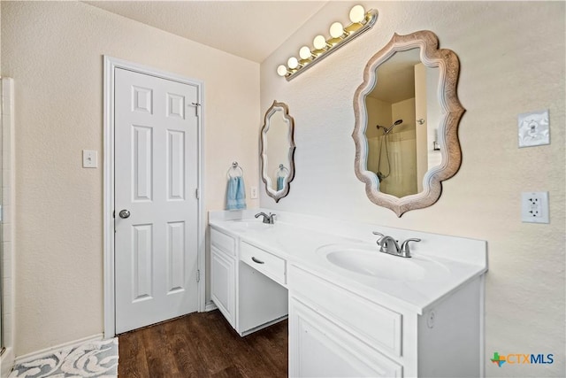 full bath featuring double vanity, wood finished floors, walk in shower, and a sink